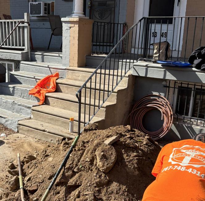 Plumber digging near the front porch of a house next to some steps